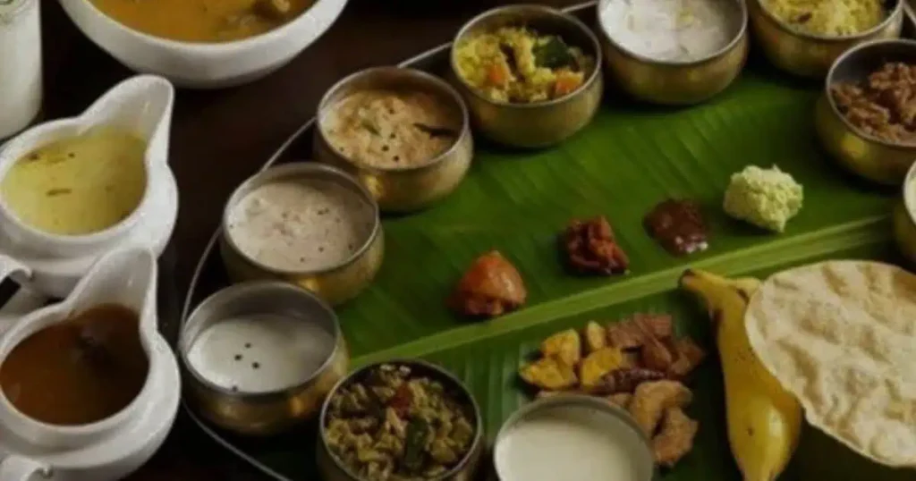 A big green leaf on which differnt kathiawadi kitchen cuisine is placed.